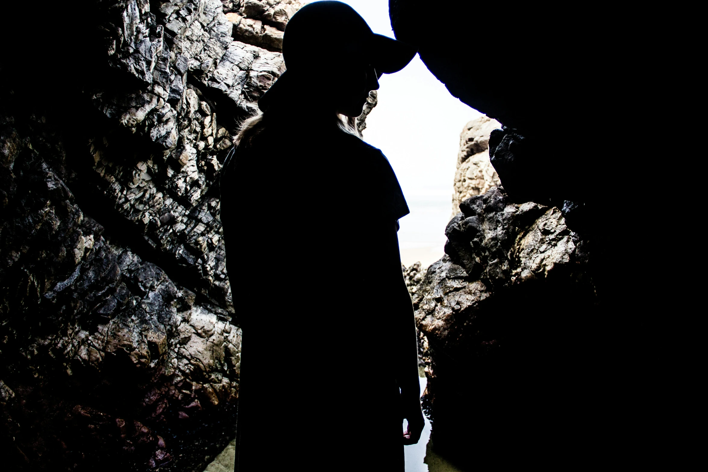 the person in a black hat is standing near rocks