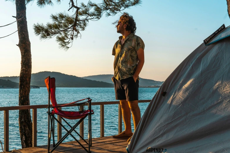 man standing on wooden dock near large lake