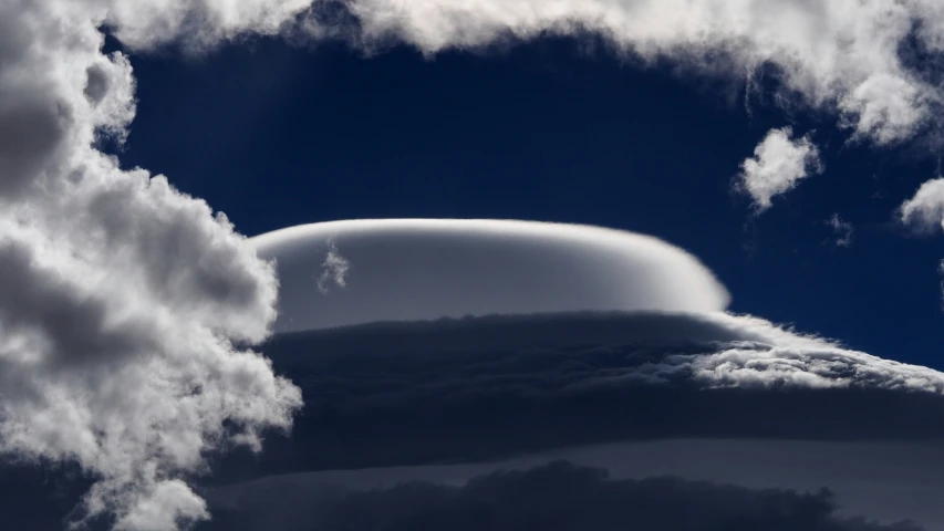 a bird flying through a large blue cloudy sky