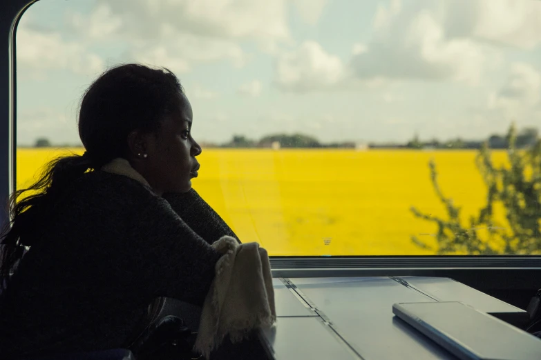 an empty table next to the window, with a woman looking out