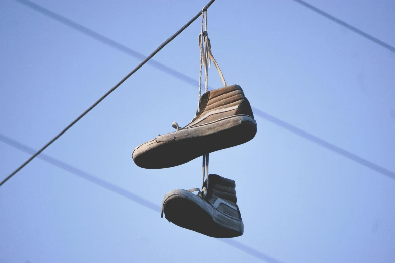 two shoes hanging from wires near each other