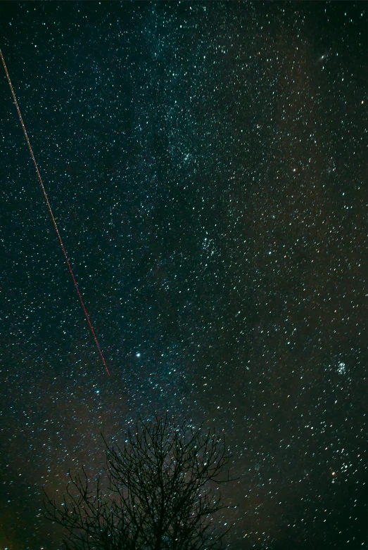 a night sky with several stars and an airplane streaking across the sky