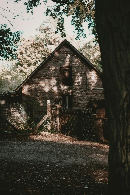 an old brick house is behind a tree