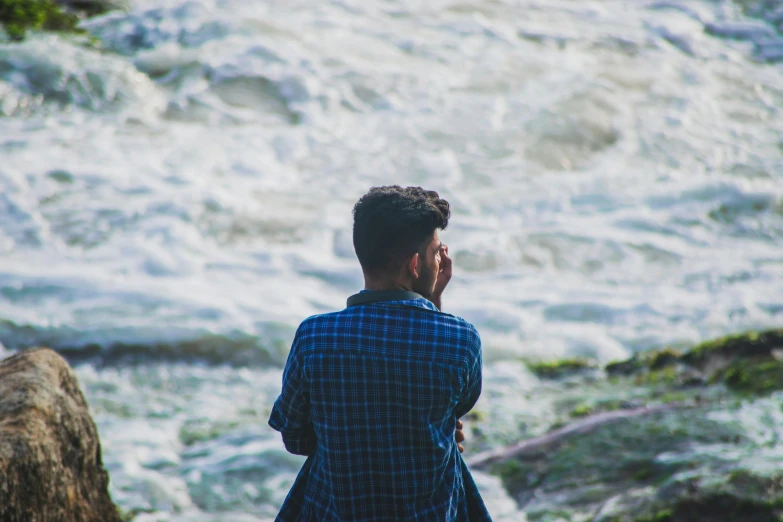 a person standing on top of a rock in front of a body of water