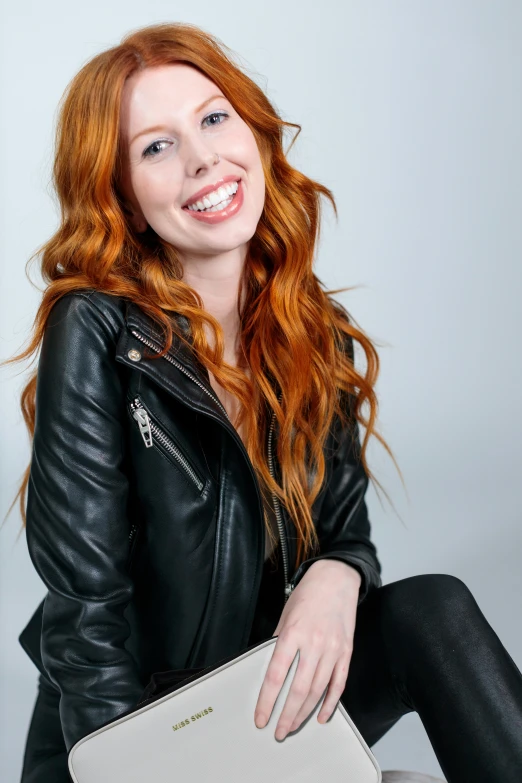 a smiling red haired woman wearing black leather jacket