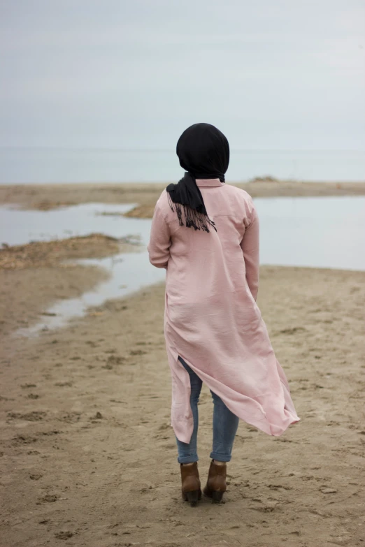 a woman walking towards the ocean on a beach