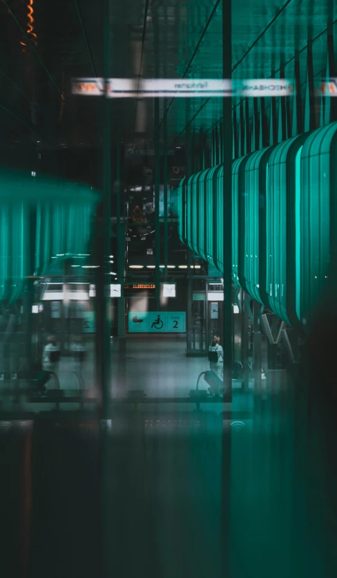 a very long hallway with some seats and green lights