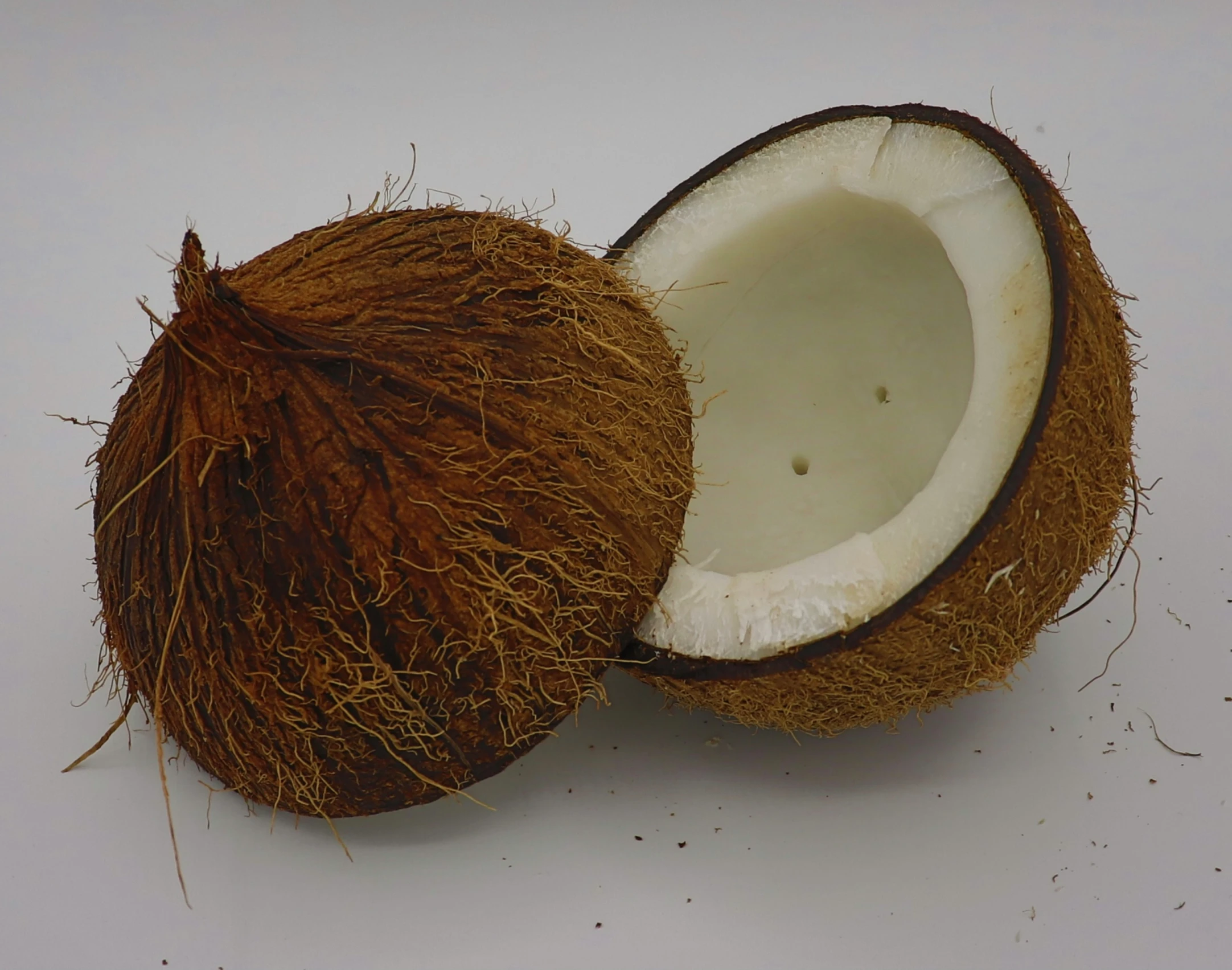 a cut open coconut with one peeled and one empty