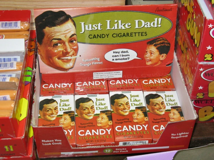 a box of just like dad candy cigarettes sits next to a display case