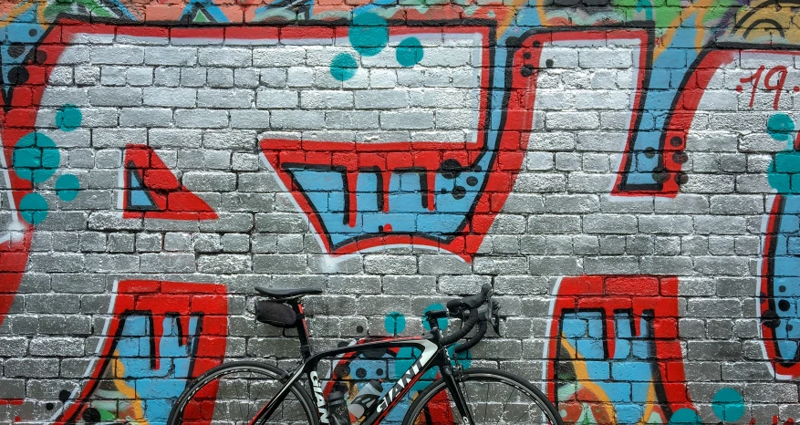 a bicycle parked against a wall with graffiti