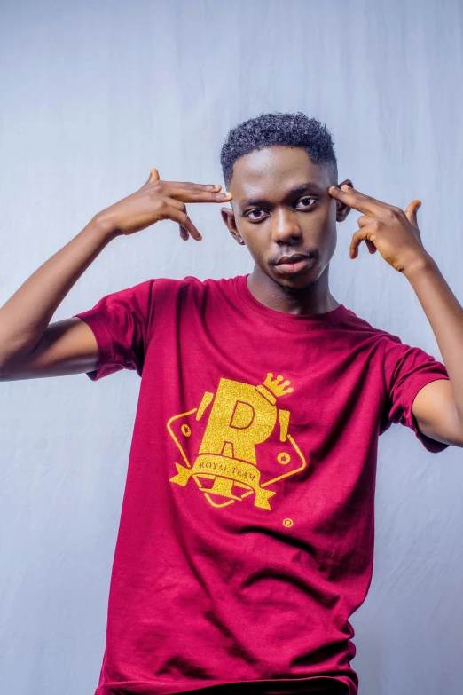 a young man poses with his hands on his head