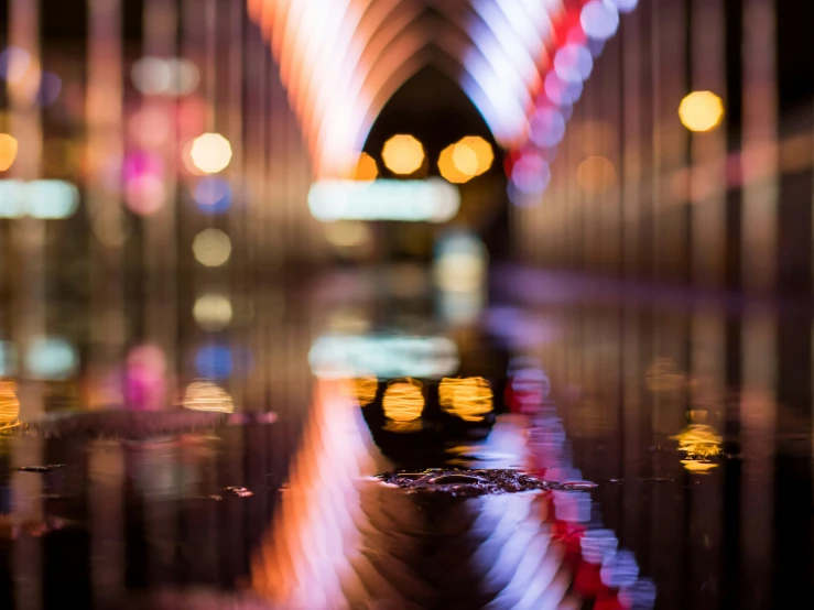 view of city street from water reflecting on surface of urban sidewalk at night