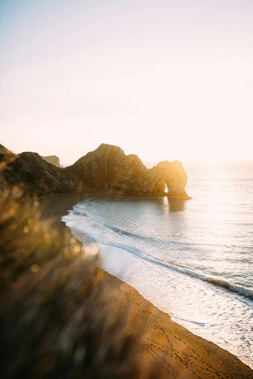 a beach with waves and rocks at sunrise