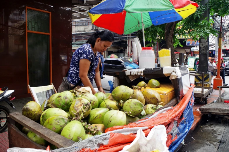 a woman is selling fruit at the sidewalk market