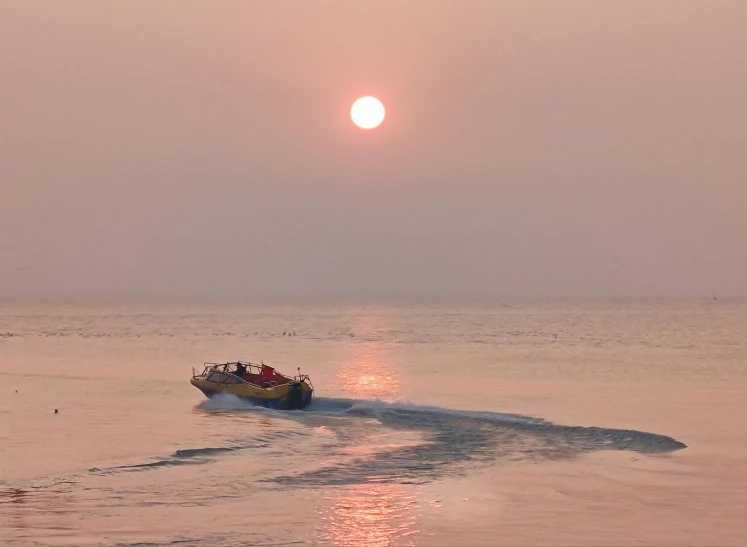 the sun is rising over the horizon as boat travels through the water