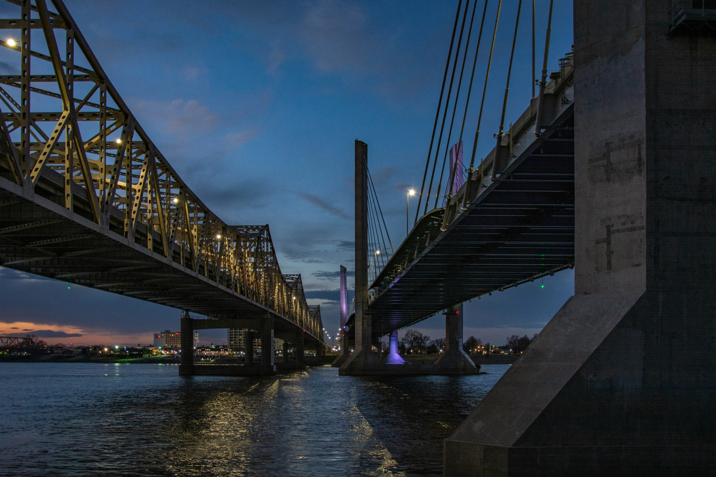 a bridge spanning the width of a river and lit up at night