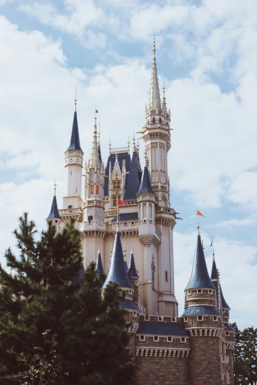 a castle with towers surrounded by trees and clouds