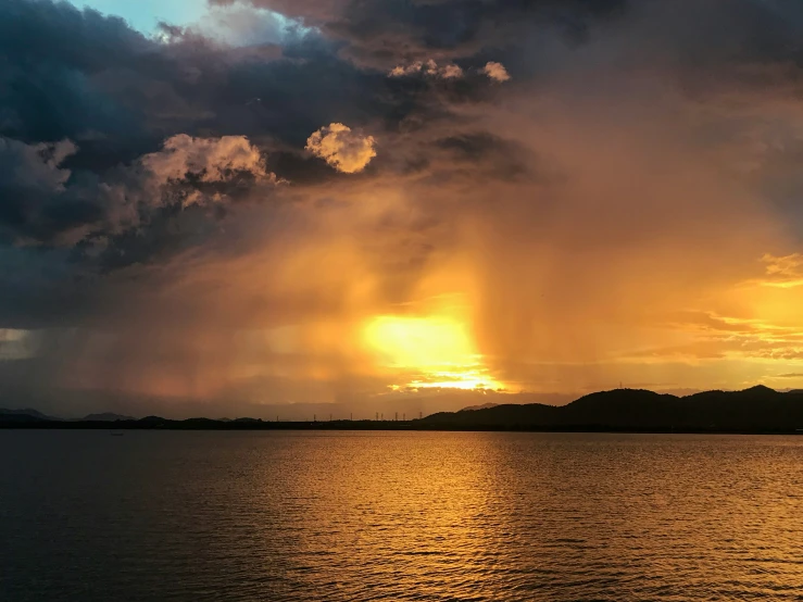 the sun is shining through clouds over water