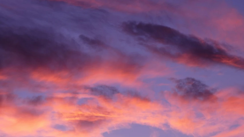 a pink sky with clouds and a jetliner