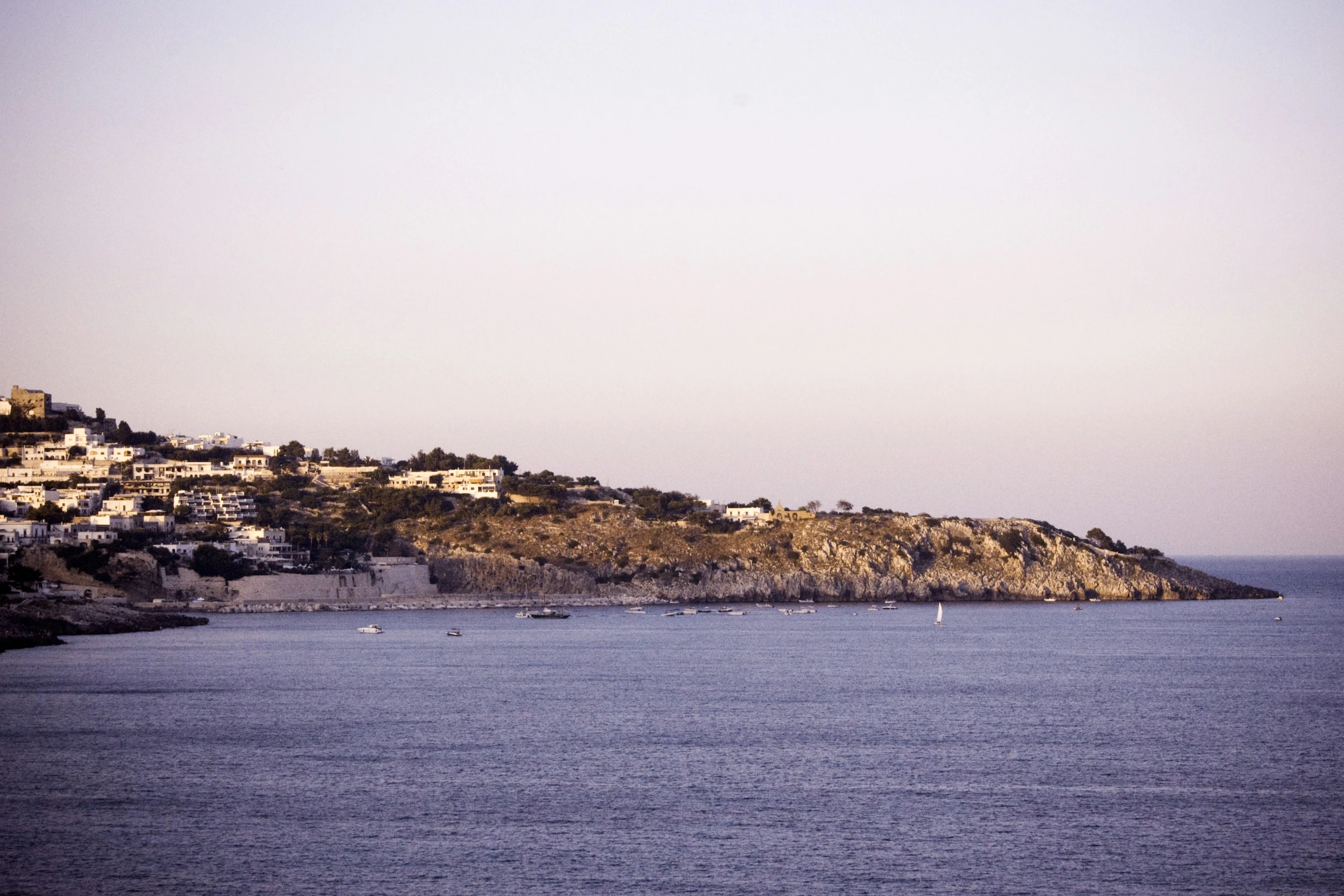 a body of water next to a hillside with a town