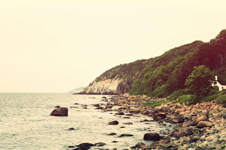 an ocean cliff with rocks at the shore