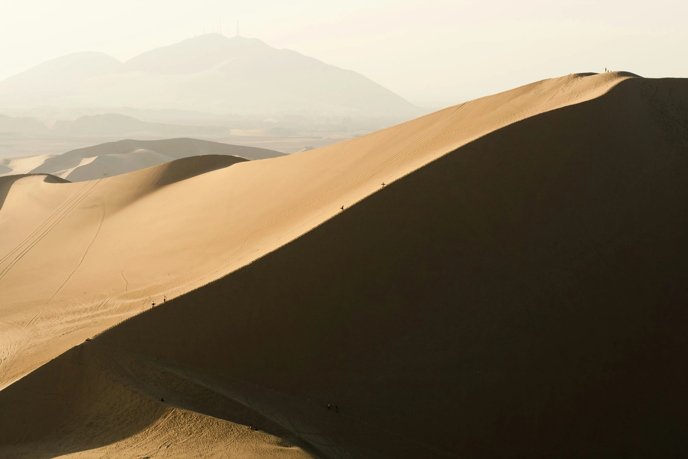 sand dunes in a desert, with mountain range behind them