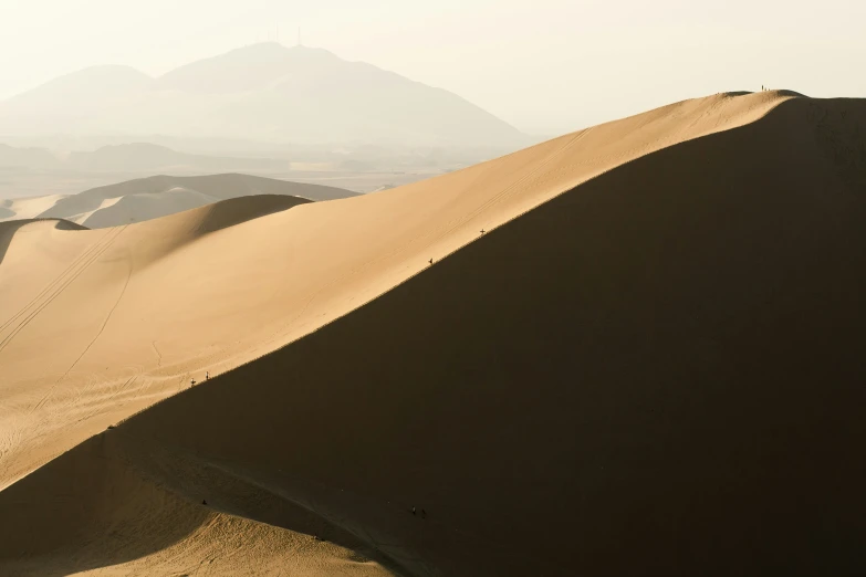 sand dunes in a desert, with mountain range behind them