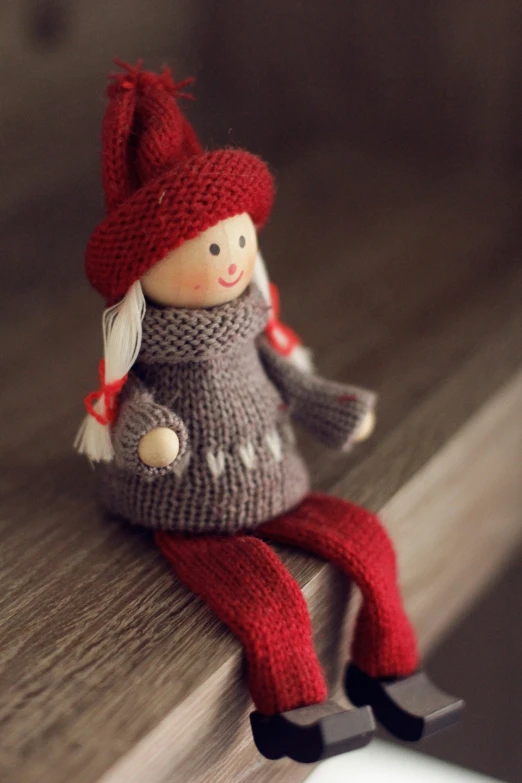 a small toy doll sitting on the edge of a wooden table