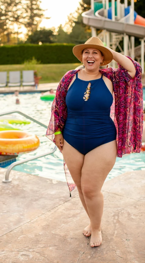 a woman in a swimsuit by a pool wearing a sun hat