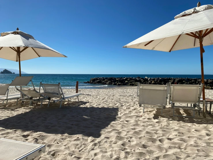 beach chairs and umbrellas are set up on a sandy beach