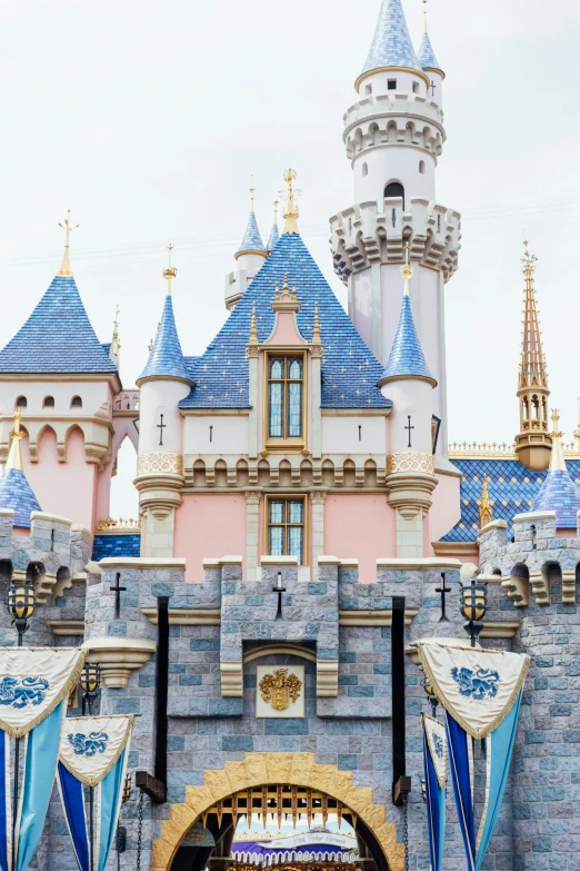 disneyland castle with blue turrets and flags on a cloudy day