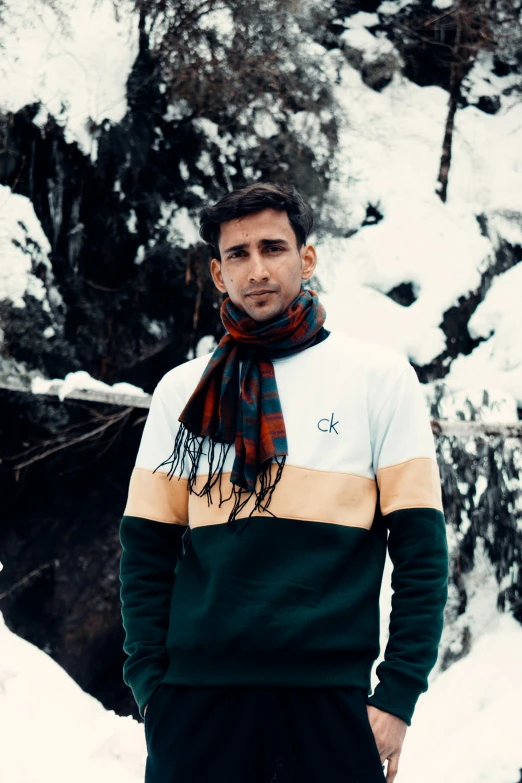 a man with a plaid scarf standing in front of a pile of snow