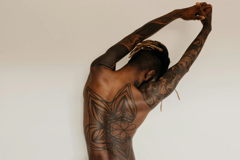 a man with tattoos on his back shows off his tattooed arm and back