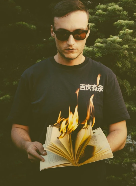 a man is holding a book in his hands with flames all over it