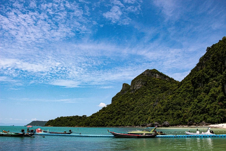 people on boats in the ocean and green mountains in the background