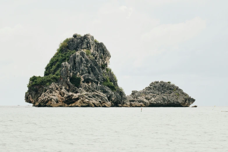 a body of water with a small island that has three large rocks on it