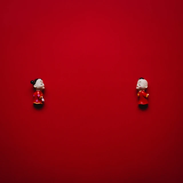 a red background with two asian style doll heads