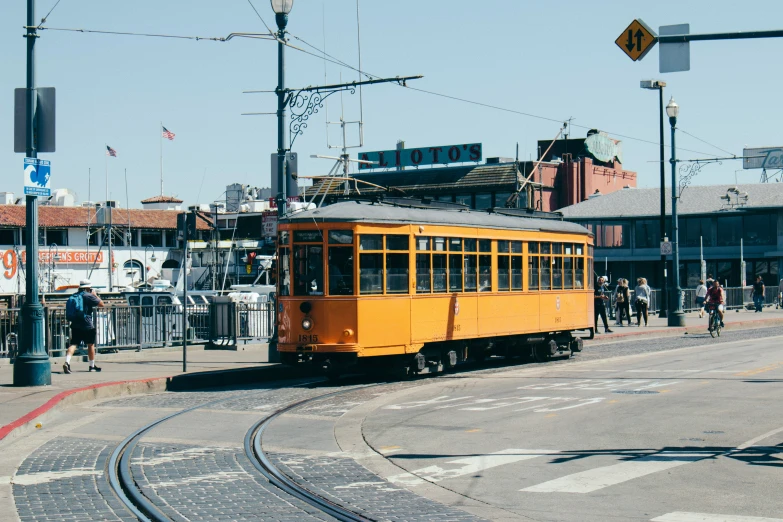 an orange trolley car parked in front of a stop sign