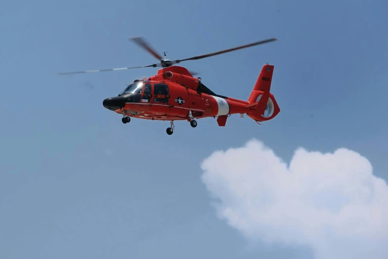 a red helicopter is flying overhead on a sunny day