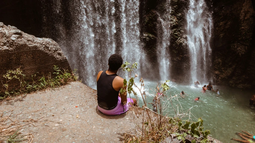 a man looking at a waterfall that is surrounded by water