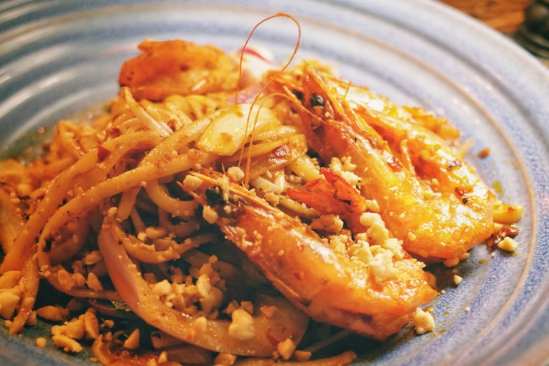 a blue plate of food with shrimp, noodles and other foods