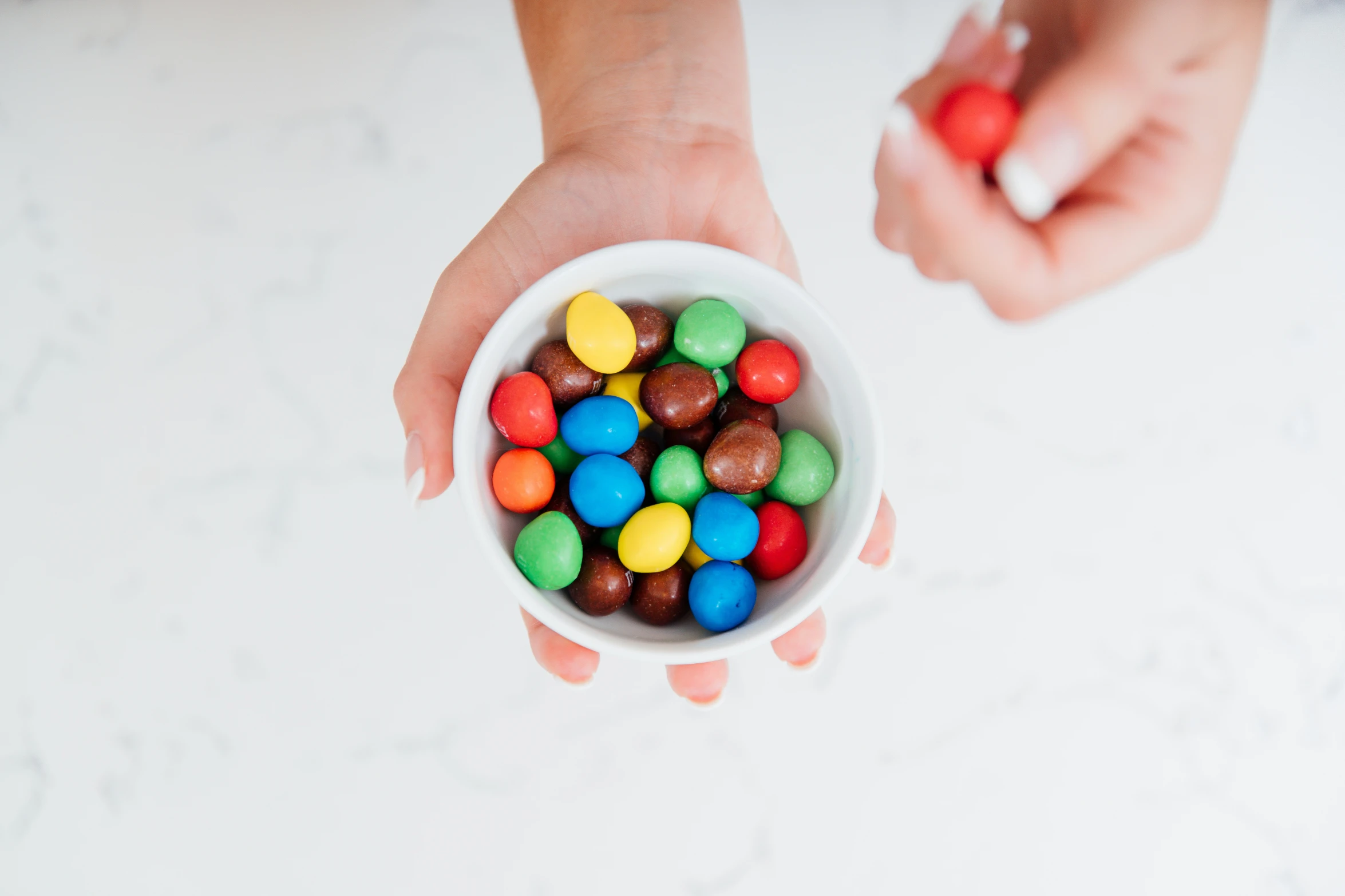 a woman is holding a bowl of candies