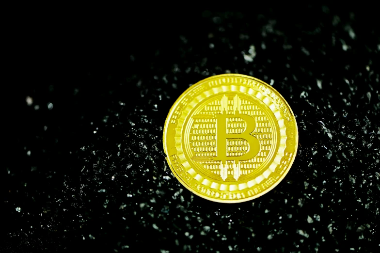 an illuminated gold bit coin on a black surface