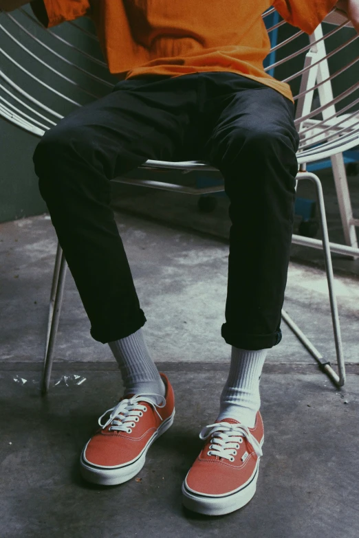 a man sitting on a chair with orange shoes