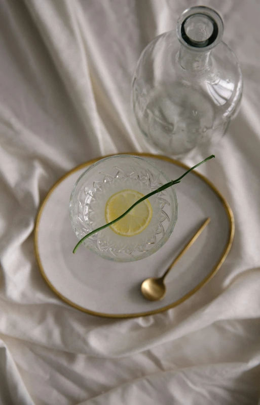 there is a glass and a white plate with lemon slices on it