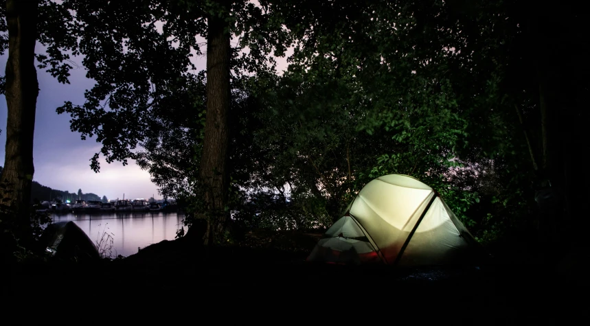 a tent set up next to the river at night