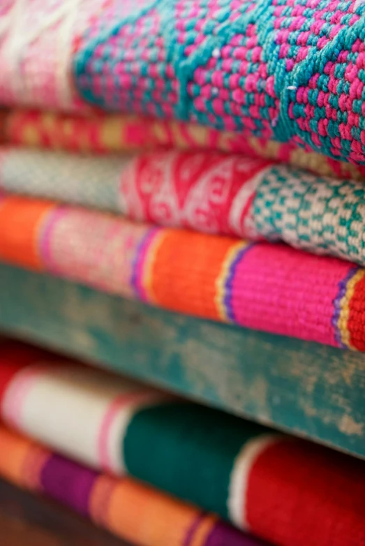 stack of colorful fabric on wooden table in room