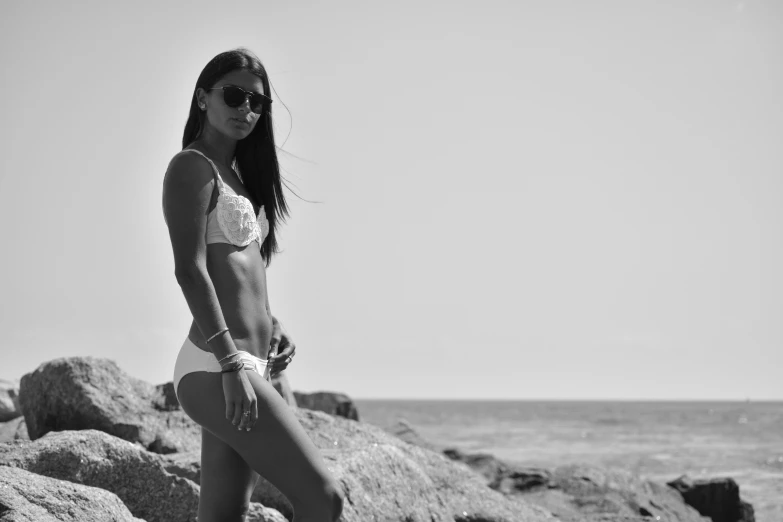 a woman standing on some rocks in front of the ocean