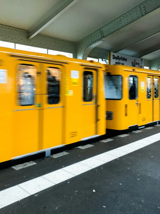 a yellow commuter train with passengers inside at a station