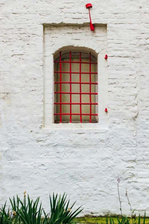 there is a white stucco house with red and gray bars